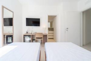 a white bedroom with two beds and a desk at Dimore delle Zagare Molo in Syracuse