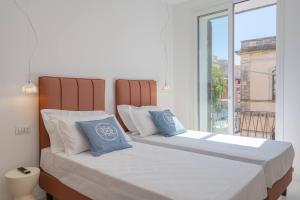 two beds with blue pillows in a room with a window at Dimore delle Zagare Molo in Syracuse
