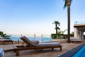 a lounge chair sitting next to the ocean at Villa Zagara Garden Spectacular Sea View in Taormina in Taormina