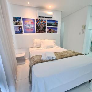 Dormitorio con cama blanca con posters en la pared en Porto Sol by AFT - PORTO DE GALINHAS en Porto de Galinhas