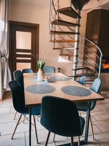 a dining room table with chairs and a spiral staircase at Fotuso House in Majdany Wielkie