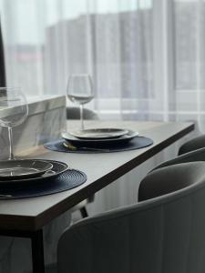 una mesa con dos copas de vino y platos en ella en Lux в ЖК TALAN LIFE от Bi Group, en Atyraū