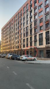 un círculo rojo al lado de un edificio con coches aparcados en Lux в ЖК TALAN LIFE от Bi Group, en Atyraū
