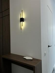 una luz en una pared blanca con una mesa de madera en Lux в ЖК TALAN LIFE от Bi Group, en Atyraū