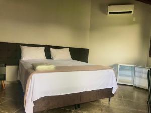 een slaapkamer met een groot bed met witte lakens bij Pousada e Camping Recanto da Praia in Capitólio