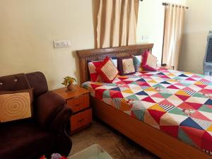 a bedroom with a bed with a colorful quilt and a chair at Khajuraho Rancho in Khajurāho