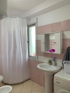 een badkamer met een wit douchegordijn en een wastafel bij Ridi's Comfort Apartment 2 in Shkodër