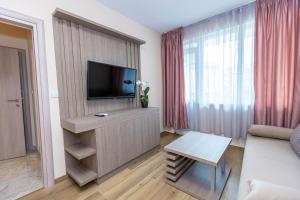 uma sala de estar com uma televisão e um sofá em Family Hotel Ambrozia em Sandanski