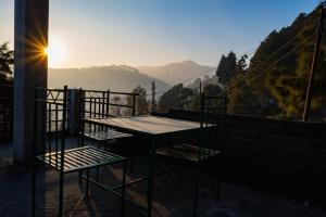 een tafel en 2 stoelen op een balkon met uitzicht op de zonsondergang bij Dew Drops Homestay in Nainital