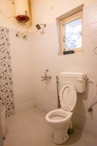 a bathroom with a toilet and a window at Dew Drops Homestay in Nainital