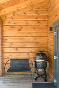 - un barbecue dans une pièce avec un banc à côté d'un mur en bois dans l'établissement Hipo House, à Utena