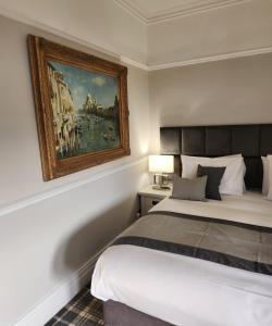 een slaapkamer met een bed en een schilderij aan de muur bij The Ryebeck Classic Country House in Bowness-on-Windermere