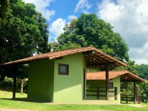 ein kleines grünes Gebäude mit einem gefliesten Dach in der Unterkunft Pousada e Camping Recanto da Praia in Capitólio