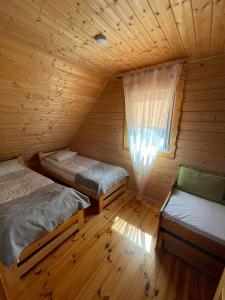Habitación con 2 camas y ventana en una cabaña de madera. en Turystyka Mazury Justyna, en Wydminy