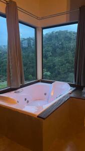 una vasca da bagno in una stanza con una grande finestra di Chalé Causo Bão a Costas