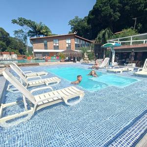 - une piscine avec des chaises longues pour un groupe de personnes dans l'établissement EcoHotel Vale do Sol, à Embu