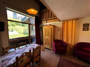 ein Esszimmer mit einem Tisch, Stühlen und einem Fenster in der Unterkunft Résidence Jetay - 3 Pièces pour 7 Personnes 464 in Les Menuires