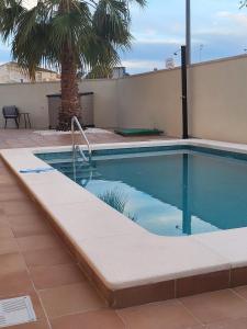 a swimming pool next to a building with a palm tree at King`s Apartaments in San Javier