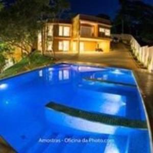 a blue swimming pool in front of a house at Espaco Bom Viver in Jundiaí