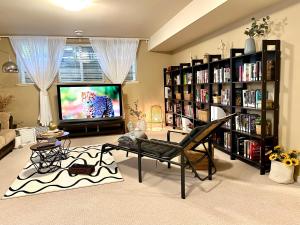 sala de estar con TV y estanterías de libros en Langley 半地下室独立出入温馨卧房-桐花草堂 en Langley