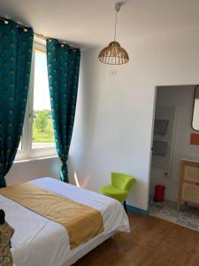 een slaapkamer met een bed en een groene stoel bij Les chambres du Phare in Le Port-des-Barques