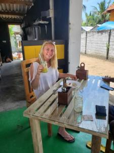 uma mulher sentada à mesa a segurar uma bebida em Surf And Stay Arugam Bay em Baía de Arugam