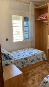 a small bedroom with a bed and a window at Achakar in Tangier