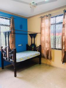 a bedroom with a bed with blue walls and windows at Fumba House BnB in Fumba