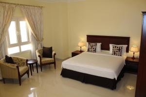 a bedroom with a bed and two chairs and a window at Nizwa Hotel Apartments in Nizwa