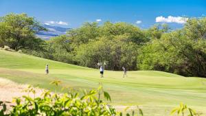 a group of people playing golf on a golf course at MAUNA KEA SUNSETS Gorgeous 2BR Kumulani Condo with Ocean Sunset View in Hapuna Beach