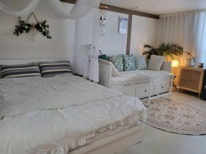 a white bedroom with a bed and a couch at Cottenbeach2 in Sokcho