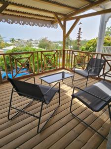 three chairs and a table on a wooden deck at Ti Oasis SEAVIEW, Studio Vue Mer à 150m de la plage in Corps de Garde