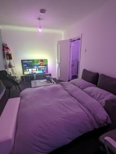 um quarto com uma cama roxa e uma televisão em Ali's Flat em Londres