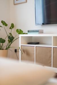 a white entertainment center with a tv and a plant at Soulplace Studioapartment Herten in Herten +15 photos