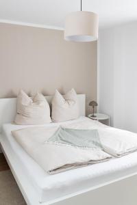 a white bed with white sheets and pillows at Soulplace Herten - warm & gemütlich in Herten