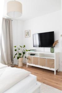 a white living room with a television on a white cabinet at Soulplace Herten - warm & gemütlich in Herten