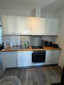 a kitchen with white cabinets and a sink at FeWo Krabbe in Wilhelmshaven