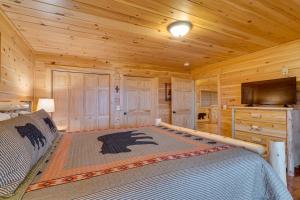 Blockhausschlafzimmer mit einem Bett und einem Flachbild-TV in der Unterkunft Gatlinburg Cabin in the Clouds with Hot Tub and Views! in Gatlinburg