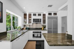 a kitchen with white cabinets and a marble counter top at Summer Estate - Pool Parking & Prime Location in Miami