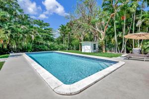 a swimming pool in a yard with an umbrella at Summer Estate - Pool Parking & Prime Location in Miami