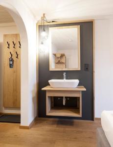 ein Bad mit einem Waschbecken und einem Spiegel in der Unterkunft Hotel Pinzgauerhof Ski & Bike - Inclusive Joker Card in Saalbach-Hinterglemm