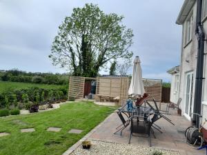 a patio with an umbrella and chairs and a garden at Close to Lough Rynn Castle Mohill - Room Only in Mohill