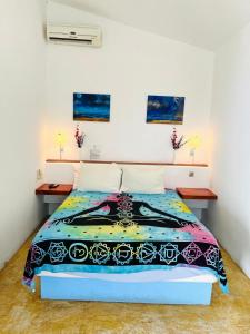een slaapkamer met een bed met een kleurrijk dekbed bij Casa de las Olas Surf & Beach Club in Acapulco