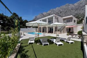 a house with a yard with chairs and a pool at Villa mia Mirela in Makarska