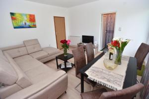 a living room with a couch and a table with flowers on it at Apartmani Mihovic - JAZ in Budva