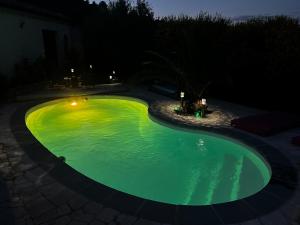 una piscina con luces verdes en un patio trasero por la noche en Partie de villa moderne avec piscine En option jaccuzi dans espace détente indépendant, en Villeneuve