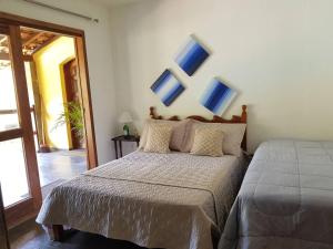 帕蒂杜阿爾費里斯的住宿－Belíssima Casa Sitio em Condomínio na Serra - Paty do Alferes，一间卧室配有一张挂着蓝色画作的床铺。