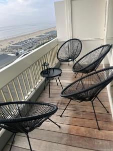 three chairs on a balcony with a view of the beach at Apartment Marmoris in Zandvoort