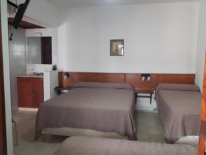 a bedroom with two beds and a kitchen with a counter at La Posada del Rey in Mina Clavero