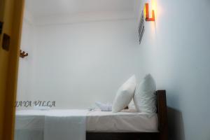 a bed with white pillows and a light on a wall at Jaya Villa in Negombo